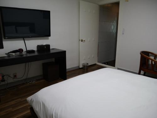 a hotel room with a bed and a flat screen tv at Jeonju Hansung hotel in Jeonju