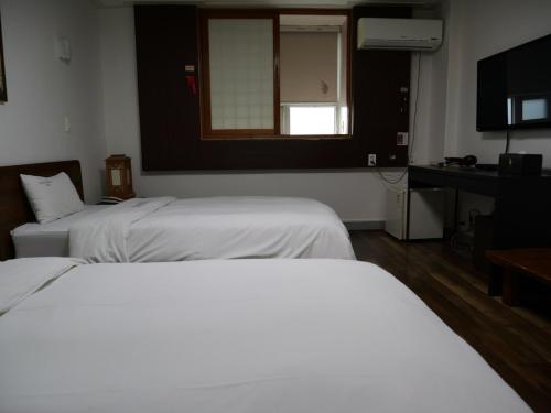 a hotel room with two beds and a television at Jeonju Hansung hotel in Jeonju