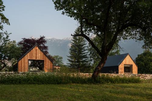una casa de madera en un campo con un árbol en Telaj Residence - Cosy Cabins near Bovec, Soča Valley, en Bovec
