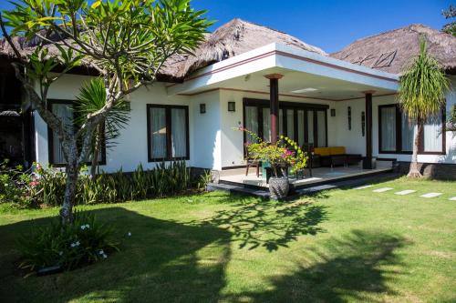 a white house with a garden and a yard at Villa L'Orange Bali in Keramas