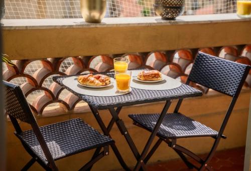 une table avec deux assiettes de nourriture et deux verres de jus d'orange dans l'établissement Rêve Bleu de Nice - Terrace - Beach & Tram 5 min, à Nice