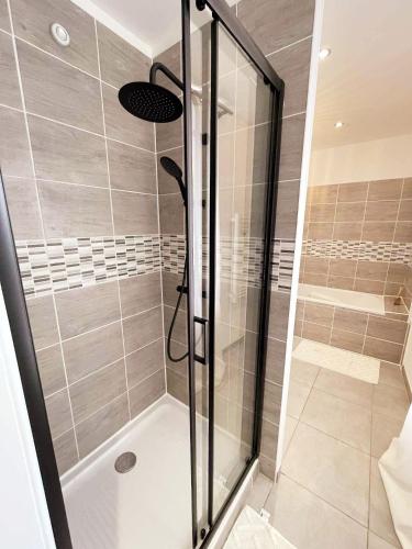 a shower with a glass door in a bathroom at La Maison de Mélou in Troarn