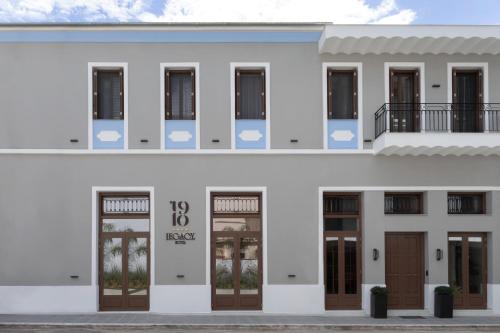 Una fachada de un edificio blanco con puertas marrones. en 1910 Legacy Hotel, en Volos