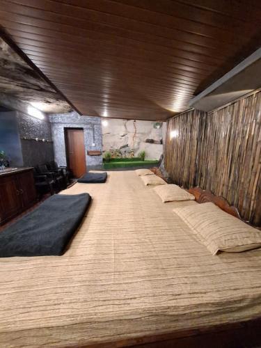 un grande letto in una stanza con molti cuscini sopra di Escape Natural Farm Stay - Cave a Kanthalloor