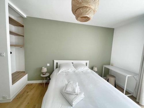 une chambre avec un grand lit blanc avec deux serviettes dessus dans l'établissement Le Wilson, à Vannes