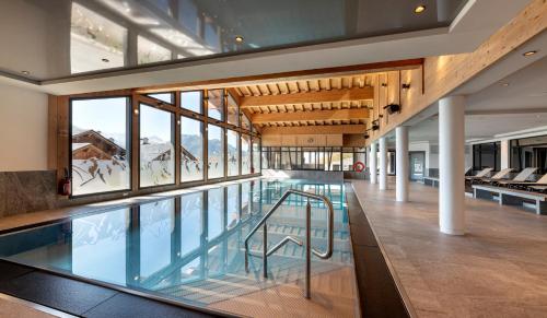 - une piscine dans un bâtiment avec fenêtres dans l'établissement MGM Hôtels & Résidences - Résidence Alpen Lodge, à La Rosière