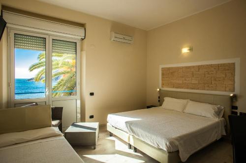 a bedroom with a bed and a view of the ocean at Hotel Calamosca in Cagliari