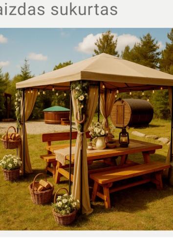 a picnic table under an umbrella with baskets and flowers at Šilas in Degučiai
