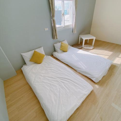 two beds in a room with white sheets and yellow pillows at 綠島夏御 微熱海岸 in Green Island