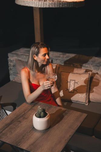 a woman sitting at a table with a drink at La Brise Luxury Suites in Néa Péramos