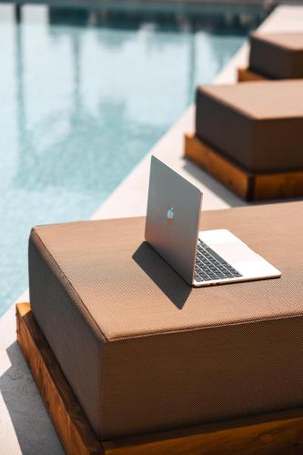a laptop computer sitting on a table next to a pool at La Brise Luxury Suites in Néa Péramos