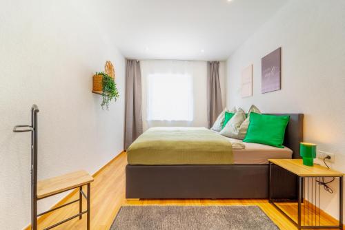 a bedroom with a bed with green pillows and a window at Oetztaler Lausbubenhaus Max & Moritz in Ötztal-Bahnhof