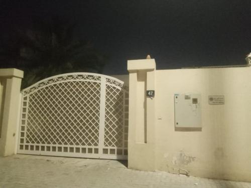a white gate in front of a building at night at Family Home in Sharjah