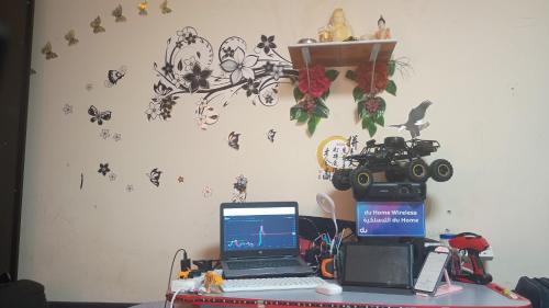a desk with a laptop and a camera on a wall at Family Home in Sharjah