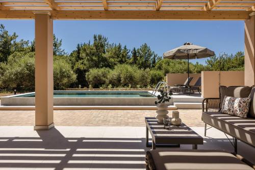 a patio with a couch and an umbrella and a pool at SOUND OF SEA Villas in Lixouri
