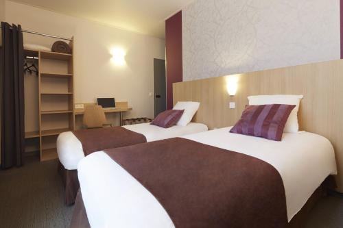 a hotel room with two beds and a desk at Hotel Paris Villette in Paris