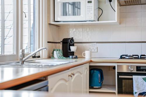 a kitchen with a sink and a microwave at Whispering Pines Cottages in Wentworth Falls