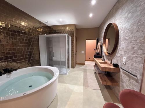 une salle de bain avec une grande baignoire et un miroir dans l'établissement La Maison Coloniale Suites privatives de luxe, à Torreilles