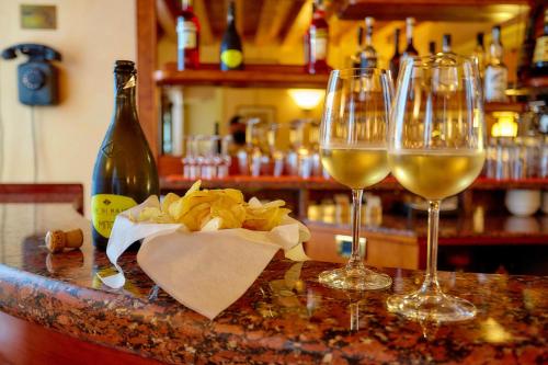two glasses of white wine and a bottle of alcohol at Hotel Riviera dei Dogi in Mira
