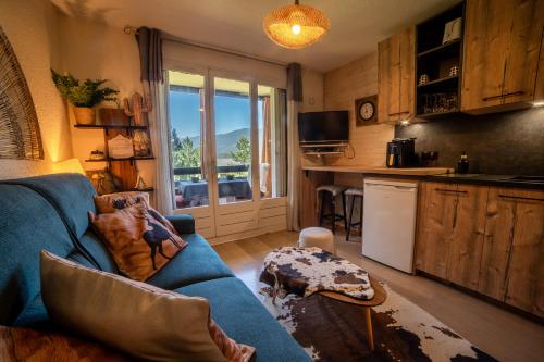 un salon avec un canapé bleu et une cuisine dans l'établissement Petit cocon plein sud vue montagnes Lesclesdenicole, à Barcelonnette