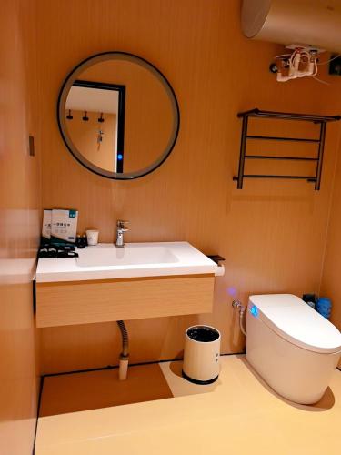 a bathroom with a sink and a toilet and a mirror at Yushe Shiguang Xiaozhu in Jining