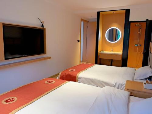 a hotel room with two beds and a flat screen tv at Yushe Shiguang Xiaozhu in Jining