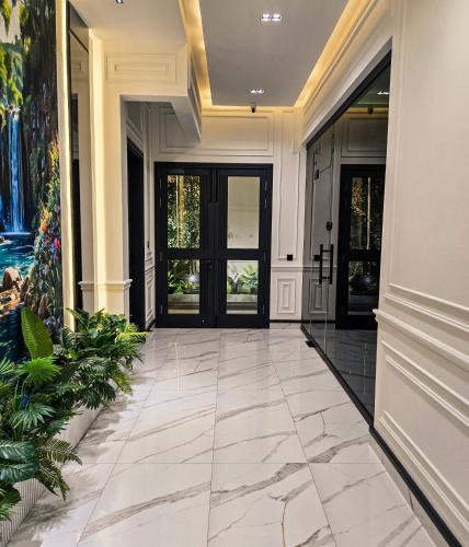 a hallway of a home with black doors and marble floors at The White Suites in Karachi