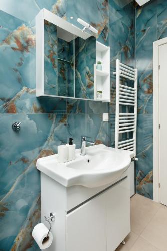 a bathroom with a white sink and a blue wall at Adorable Modern Guesthouse 3 in Perea