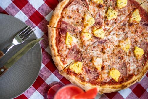 a pizza sitting on top of a table with a plate at Hotel Blambangan in Banyuwangi