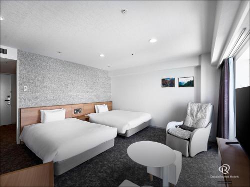 a hotel room with two beds and a chair at Daiwa Roynet Hotel Numazu in Numazu