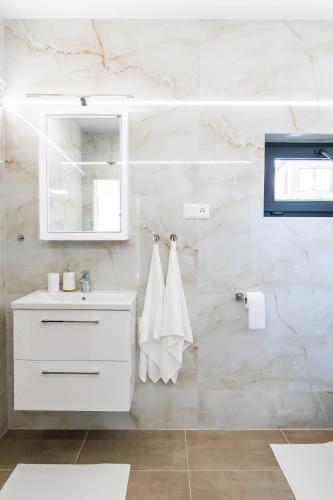 a white bathroom with a sink and a mirror at Chata Kotva White House in Trstená