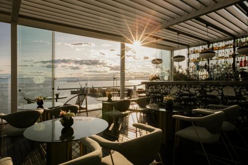 a bar with tables and chairs and a view of the ocean at ON Residence - Small Luxury Hotels of the World in Thessaloniki
