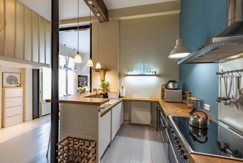 une grande cuisine avec des murs bleus et des placards blancs dans l'établissement Loft Paris centre, à Paris