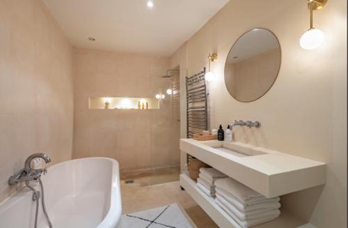 une salle de bain avec un lavabo, une baignoire et un miroir dans l'établissement Loft Paris centre, à Paris