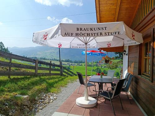 a table and chairs under an umbrella on a porch at Apartment Haus Klingspitz Pilzegg in Embach