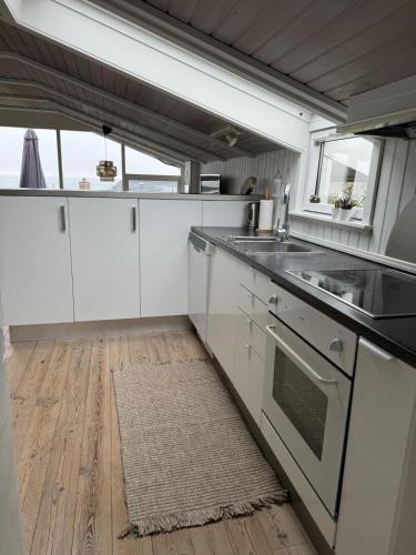 a kitchen with white cabinets and a wooden floor at Cozy cottage with sea view in Esbjerg