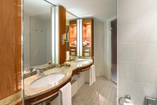 a bathroom with two sinks and a large mirror at Mercure Hotel München Airport Freising in Freising