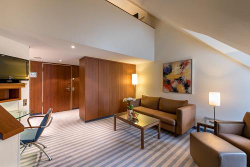 a living room with a couch and a table at Mercure Hotel München Airport Freising in Freising