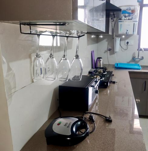a kitchen with wine glasses hanging from a rack at Elegance Beyond Ordinary Stays in Zirakpur