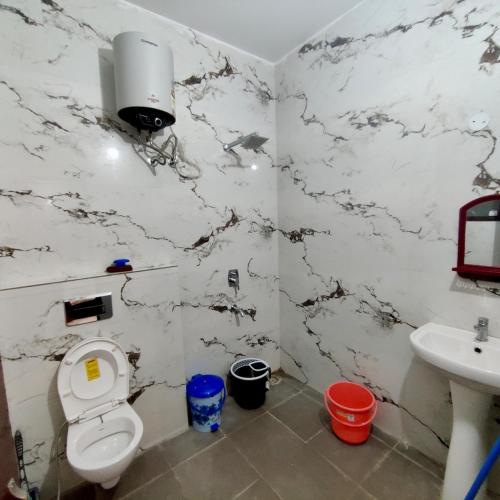 a white bathroom with a toilet and a sink at Elegance Beyond Ordinary Stays in Zirakpur