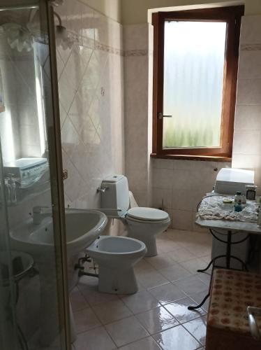 a bathroom with a toilet and a sink and a window at La casa tra i monti in Ponna Superiore