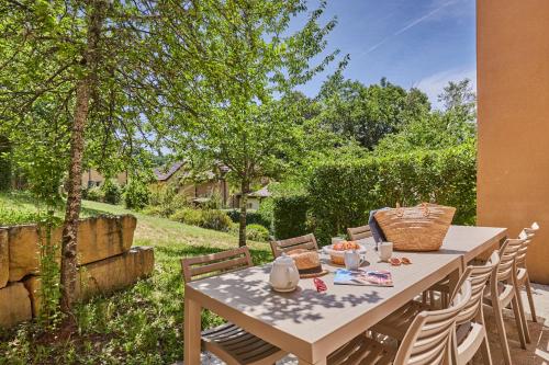 une table et des chaises dans une cour arborée dans l'établissement Résidence Odalys - Les Coteaux de Sarlat, à Sarlat-la-Canéda