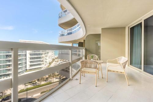 a balcony with two chairs and a table on it at Silkhaus Vacation Homes Ajwan Tower 1BR with Maid room in Saadiyat Island in Abu Dhabi