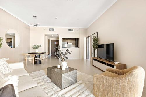 a living room with a couch and a tv at Silkhaus Vacation Homes Ajwan Tower 1BR with Maid room in Saadiyat Island in Abu Dhabi