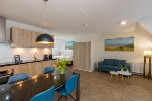 a kitchen and living room with a table and blue chairs at Welcome in - Aparthotel Zoutelande, studio's en app voor 2-6 pers - 50m van het strand in hartje centrum in Zoutelande