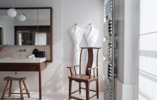 La salle de bains est pourvue de 2 chaises, d'un lavabo et d'un miroir. dans l'établissement Hotel de Pourtales, à Paris