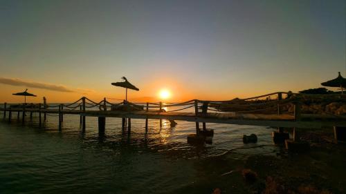 a sunset over the water with umbrellas on a beach at maison plage kerkennah in Mouamla
