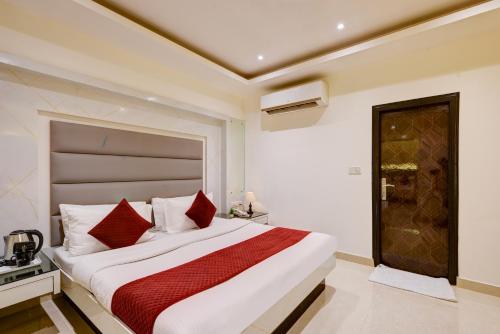 a bedroom with a large white bed with red pillows at Hotel Krishna Deluxe-By RCG Hotels in New Delhi