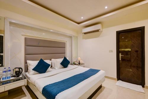 a bedroom with a large bed with blue pillows at Hotel Krishna Deluxe-By RCG Hotels in New Delhi