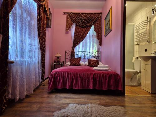a bedroom with pink walls and a bed with a window at Bocianówka in Baranów Sandomierski